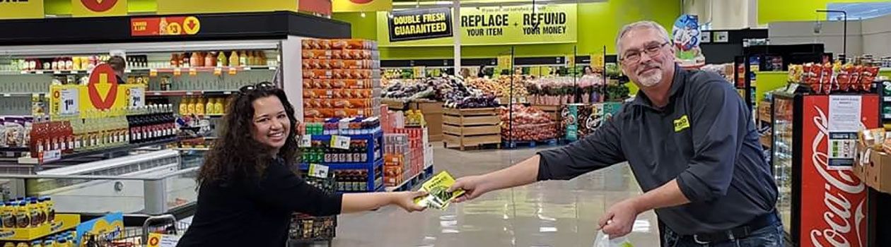 Freshco employee giving giftcards to community member