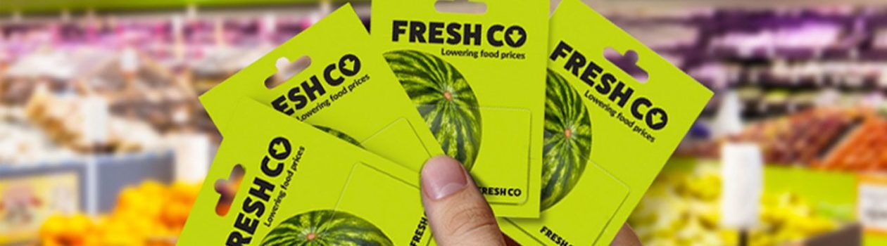 a hand holding multiple Freshco giftcards inside the store